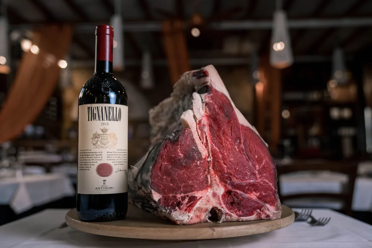 A raw T-bone for bistecca beside a bottle of Tuscan wine